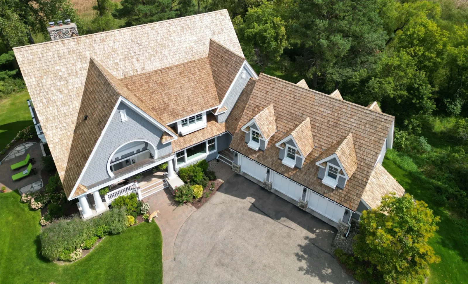 Aerial of a shingle-style home with a new cedar-shake roof, dormers and three-car garage