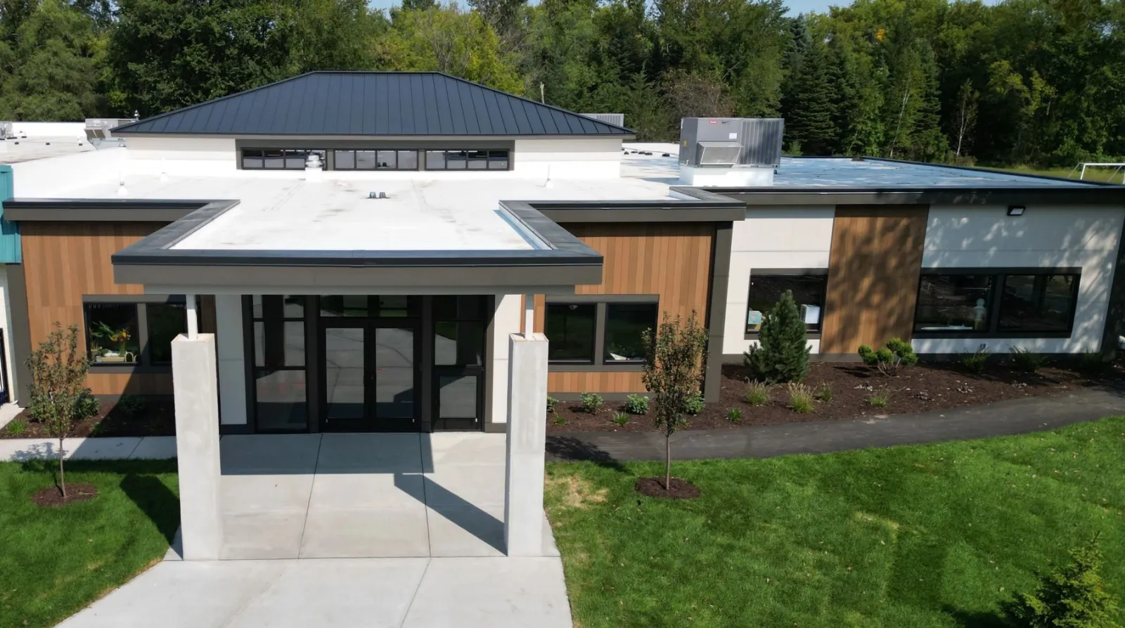 Commercial building with standing-seam metal roof, white low-slope membrane and wood siding