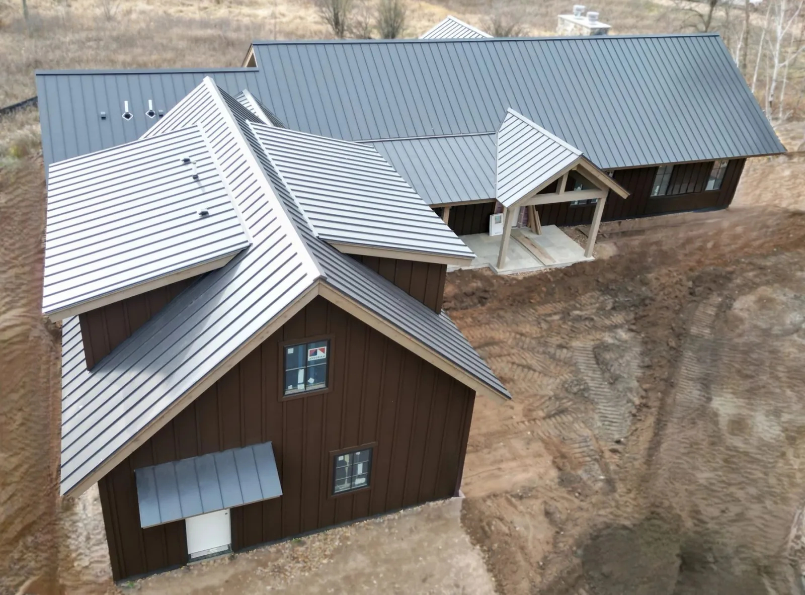 Dark bronze 24-gauge standing-seam metal roof on a board-and-batten home